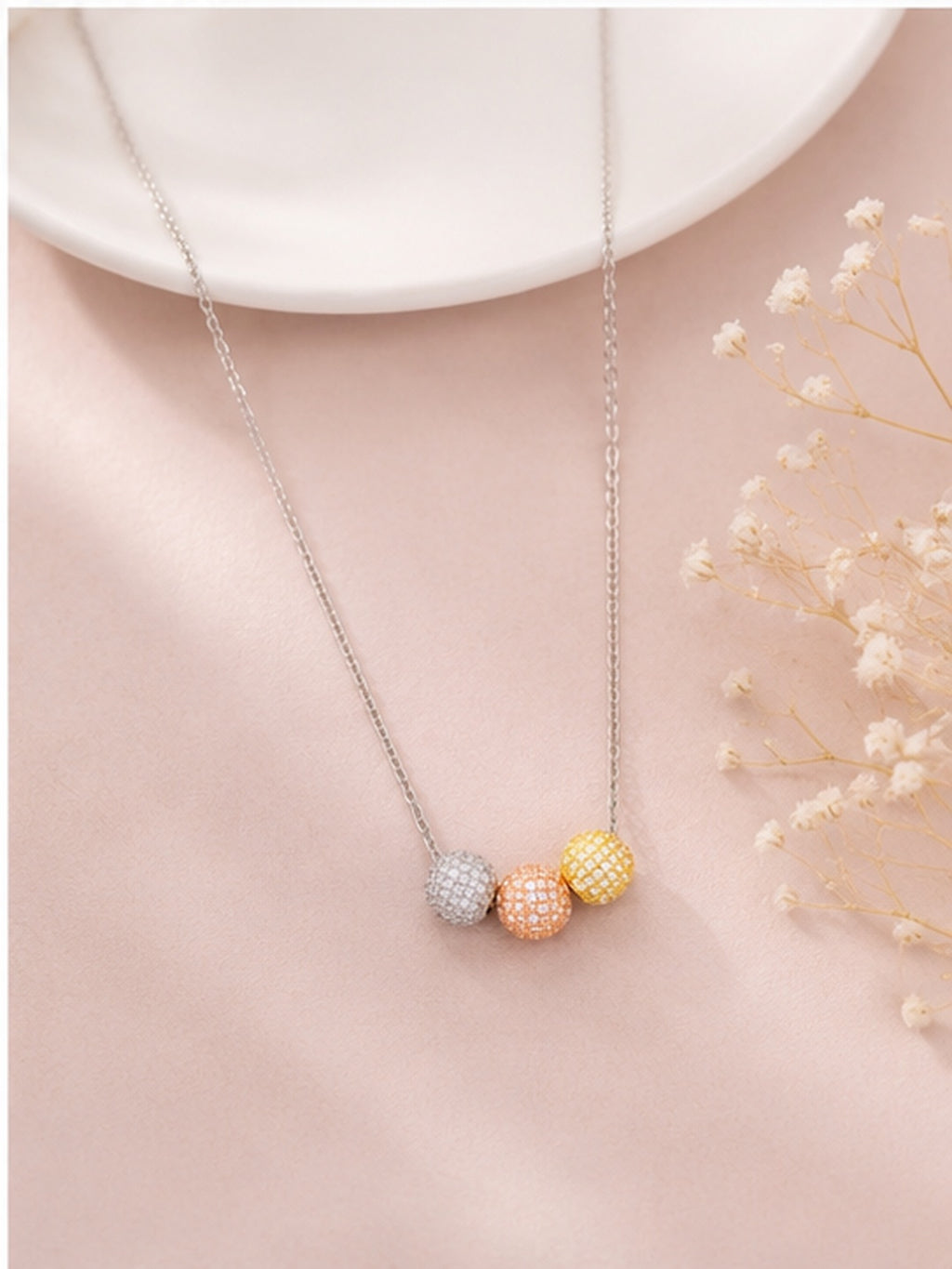 Tri-tone pavé ball necklace on blush pink background