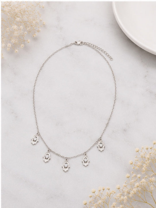 Five hamsa charm necklace on marble surface with baby's breath flowers