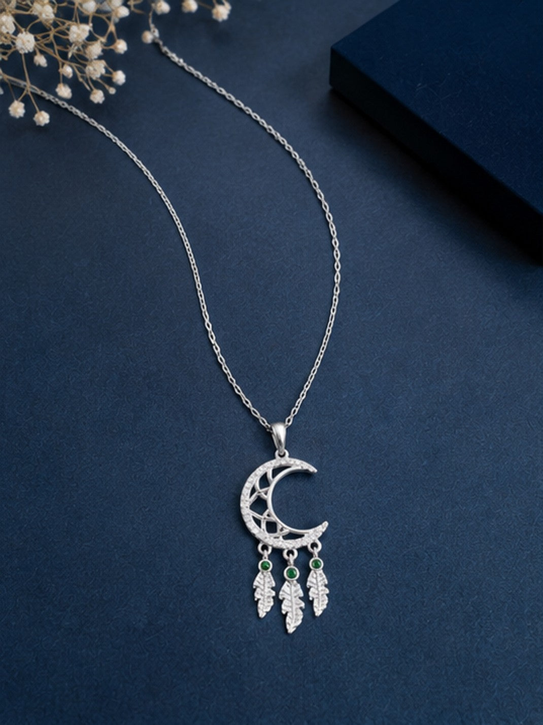 Crescent moon dreamcatcher necklace on navy blue background with baby's breath
