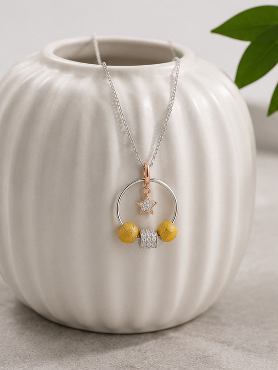 Celestial hoop star charm necklace draped on white ceramic vase