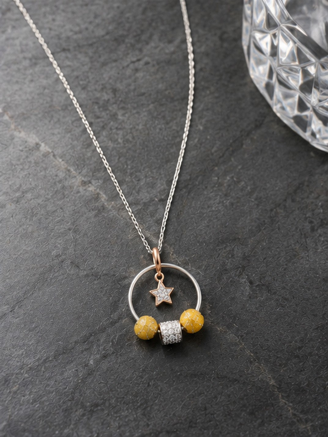 Celestial hoop star charm necklace on dark slate with crystal glass